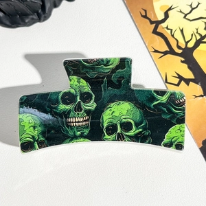 Detail of black Halloween hair claw clip featuring vibrant green skull pattern print