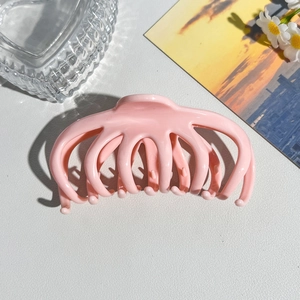 Pink octopus style hair claw clip displayed with daisy and sunset postcard
