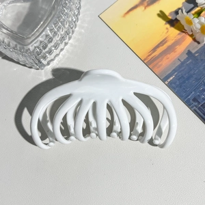 Macro shot of large octopus-shaped matte white hair claw clip with multi-tooth structure