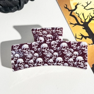 Macro shot of Halloween hair claw clip featuring white skull pattern on purple acetate material