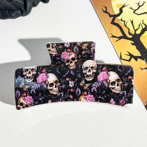 Detail of Halloween hair claw clip with realistic skull and pink flower patterns on black