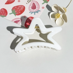 Close-up of white star-shaped hair claw clip with golden metal spring and glossy finish