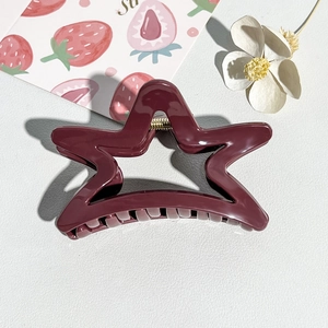 Detailed view of a glossy wine red star-shaped hair claw clip with gold metal spring