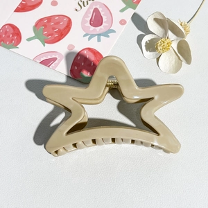 Detail view of a beige star-shaped hair claw clip with a durable gold metal spring mechanism