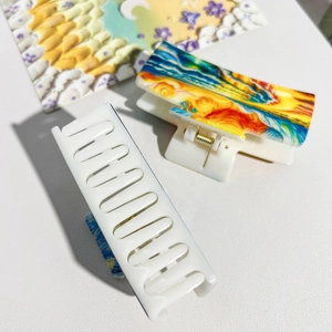 Detail view of large hair claws featuring Van Gogh star sky painting and solid white design