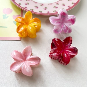 Détail de quatre petites pinces à cheveux fleur de frangipanier avec texture marbrée