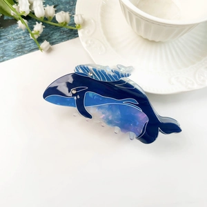 Dettaglio macro della molletta a balena in acetato blu lucido con occhio di cristallo
