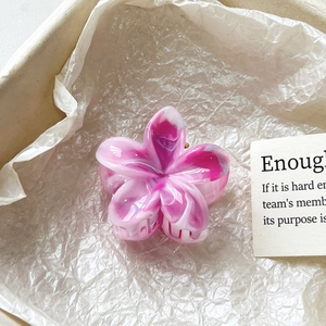 Détail d'une pince à cheveux fleur dégradé marbre rose dans une boîte cadeau élégante