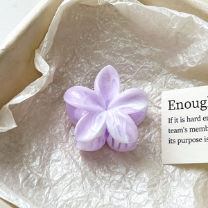 Gros plan sur la pince à cheveux fleur violette marbrée dans son coffret cadeau chic