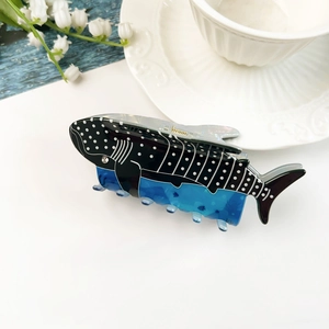 Dettaglio della molletta per capelli a squalo balena in acetato blu e nero a pois bianchi