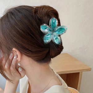 Pinza per capelli a fiore con trama marmorizzata blu su un'acconciatura elegante donna