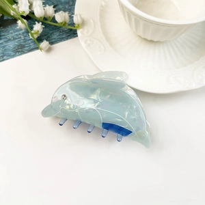 Dettaglio di una molletta per capelli a delfino blu in acetato con finitura iridescente