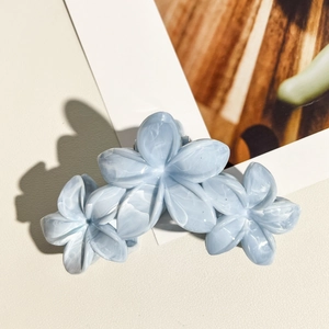 Détail d'une pince à cheveux à trois fleurs bleu clair avec texture effet marbré