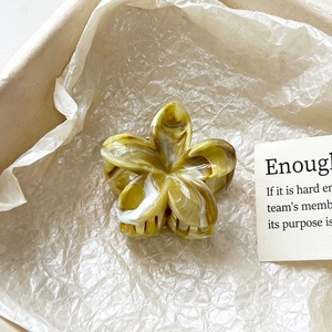 Détail de pince à cheveux fleur à texture marbrée verte dans une boîte cadeau