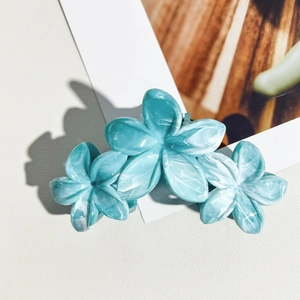 Vue détaillée de trois pinces à cheveux en acétate bleu marbré sur une carte blanche
