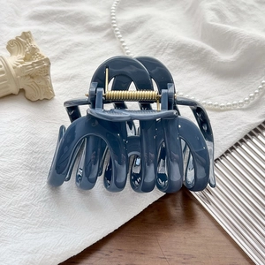 Close-up of a glossy navy blue wavy hair claw clip with a durable gold metal spring