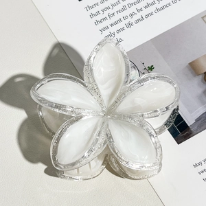 Dettaglio ravvicinato di un fermaglio per capelli a fiore bianco con bordi glitterati