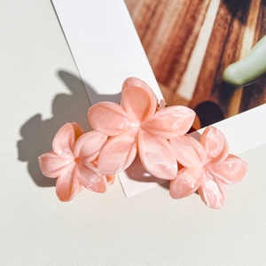 Détail de la pince à cheveux à fleurs rose marbré en acétate sur carte blanche