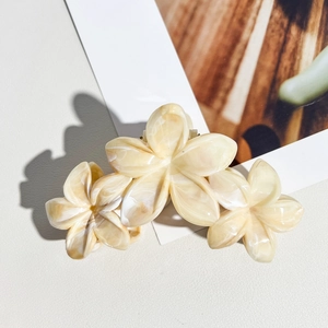 Vue détaillée de trois pinces à cheveux en forme de fleur de frangipanier marbré crème