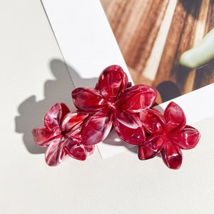 Détail de la pince à cheveux 11cm rouge bordeaux avec texture marbre et trois fleurs