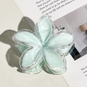 Dettaglio molletta per capelli frangipani verde chiaro con bordi glitterati su rivista