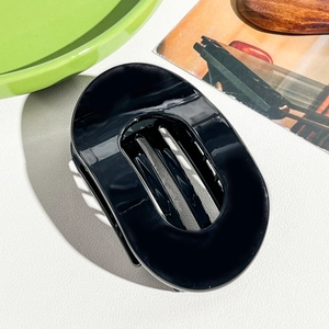Détail d'une grande pince à cheveux ovale noire avec des dents solides sur fond blanc