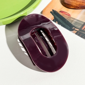 Vue détaillée d'une grande pince à cheveux ovale violet foncé avec finition brillante et dents