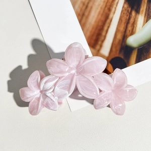 Détail d'une pince à cheveux triple fleur rose marbré sur une surface en cuir chic