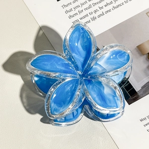 Dettaglio del fermaglio per capelli a forma di fiore azzurro con texture marmorizzata