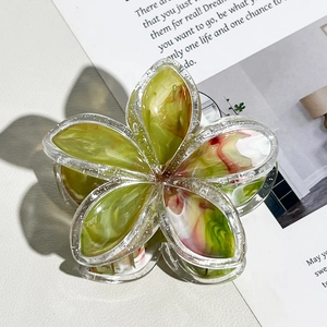 Dettaglio molletta per capelli a fiore con trama marmorea verde e bordi glitter
