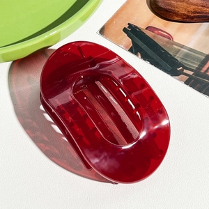 Vue détaillée d'une pince à cheveux ovale bordeaux translucide sur une surface texturée