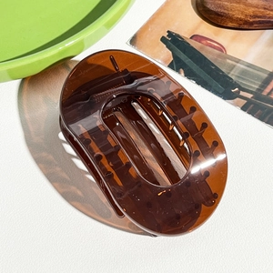 Détail de la pince à cheveux ovale en acrylique marron translucide avec dents de maintien
