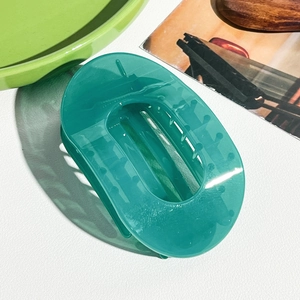 Vue détaillée d'une grande pince à cheveux ovale bleu-vert translucide au design ajouré
