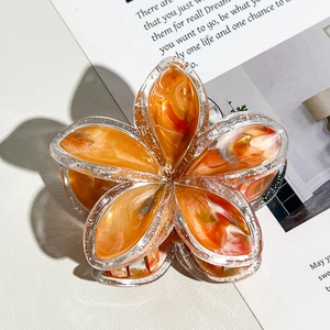 Dettaglio del fermaglio per capelli a fiore arancione marmorizzato con bordi glitter