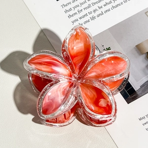 Dettaglio della molletta per capelli a fiore arancione marmorizzato con bordi glitter