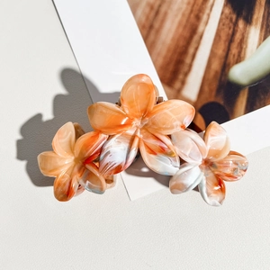 Vue détaillée de la pince à cheveux triple frangipanier avec texture marbrée orange en résine