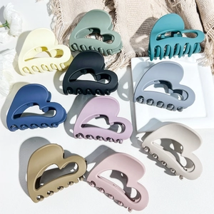 Close-up of ten matte heart-shaped hair claw clips in various Morandi colors and textures