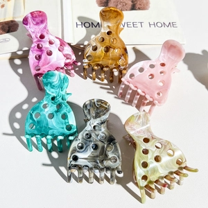 Detail view of large marble texture acrylic hair claws set with round hollow designs
