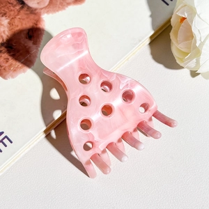 Detail of pink marble textured acetate hair claw with eight-tooth design for daily styling