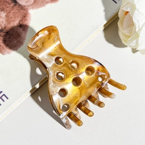 Detailed view of an amber marble acetate hair claw clip on a stylish white background
