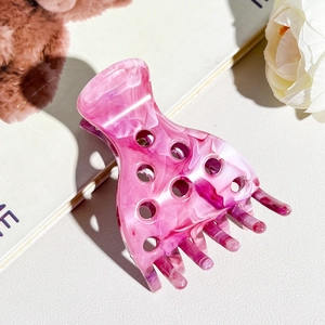 Detailed close-up of pink marble texture hair claw clip with round cutout design