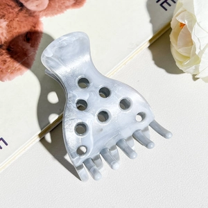Detailed close-up of grey marble pattern hair claw clip with stylish circular cutouts