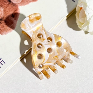 Detailed macro view of the marble texture and circular cutouts on the acetate hair claw