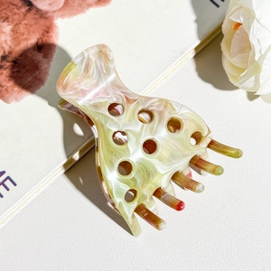 Detailed macro view of acetate hair claw clip with marble texture on magazine background