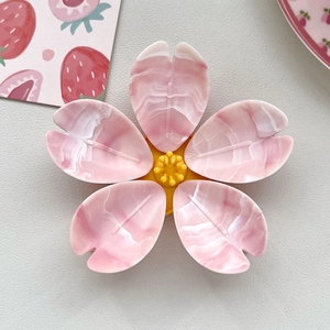 Detail view of 3D cherry blossom fridge magnet with pink marble texture and yellow center