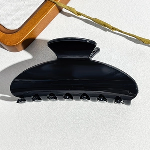 Detail of large glossy black claw clip showing smooth resin texture and deep teeth design