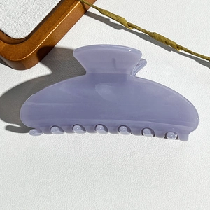 Detail of lavender purple semi-circular shark hair claw clip on minimalist background