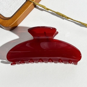 Detail of burgundy semi-transparent hair claw clip on white textured leather background