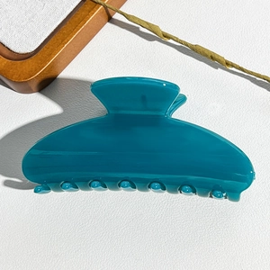 Macro detail of glossy peacock blue hair claw clip with rounded anti-slip teeth