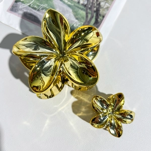 Détail de pinces à cheveux fleur de frangipanier dorées avec finition miroir brillant